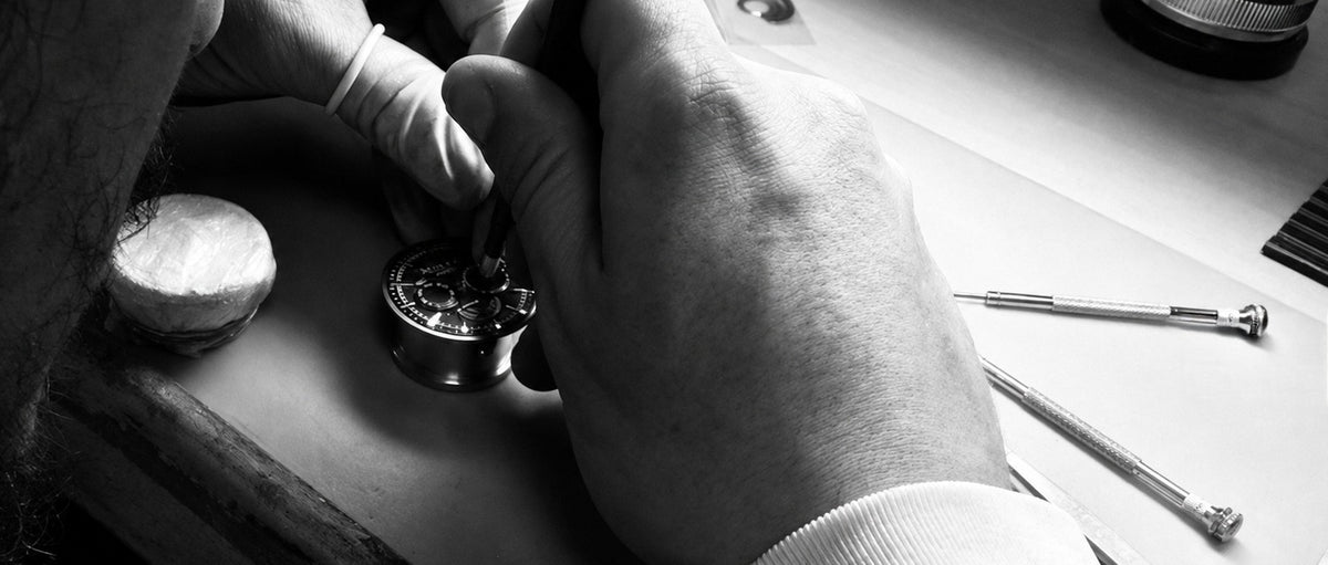 Orologiaio al lavoro al banco: assemblaggio a mano di un movimento meccanico Swiss Made nel laboratorio Tanca
